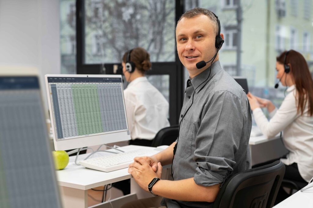 Man wearing a headset, working at a computer, representing expert support, customer service, or technical assistance.